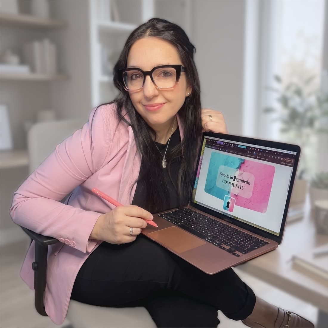 Patrizia seduta con il portatile aperto sulle ginocchia, una matita in mano, sullo schermo la pagina della community Sposta lo sguardo